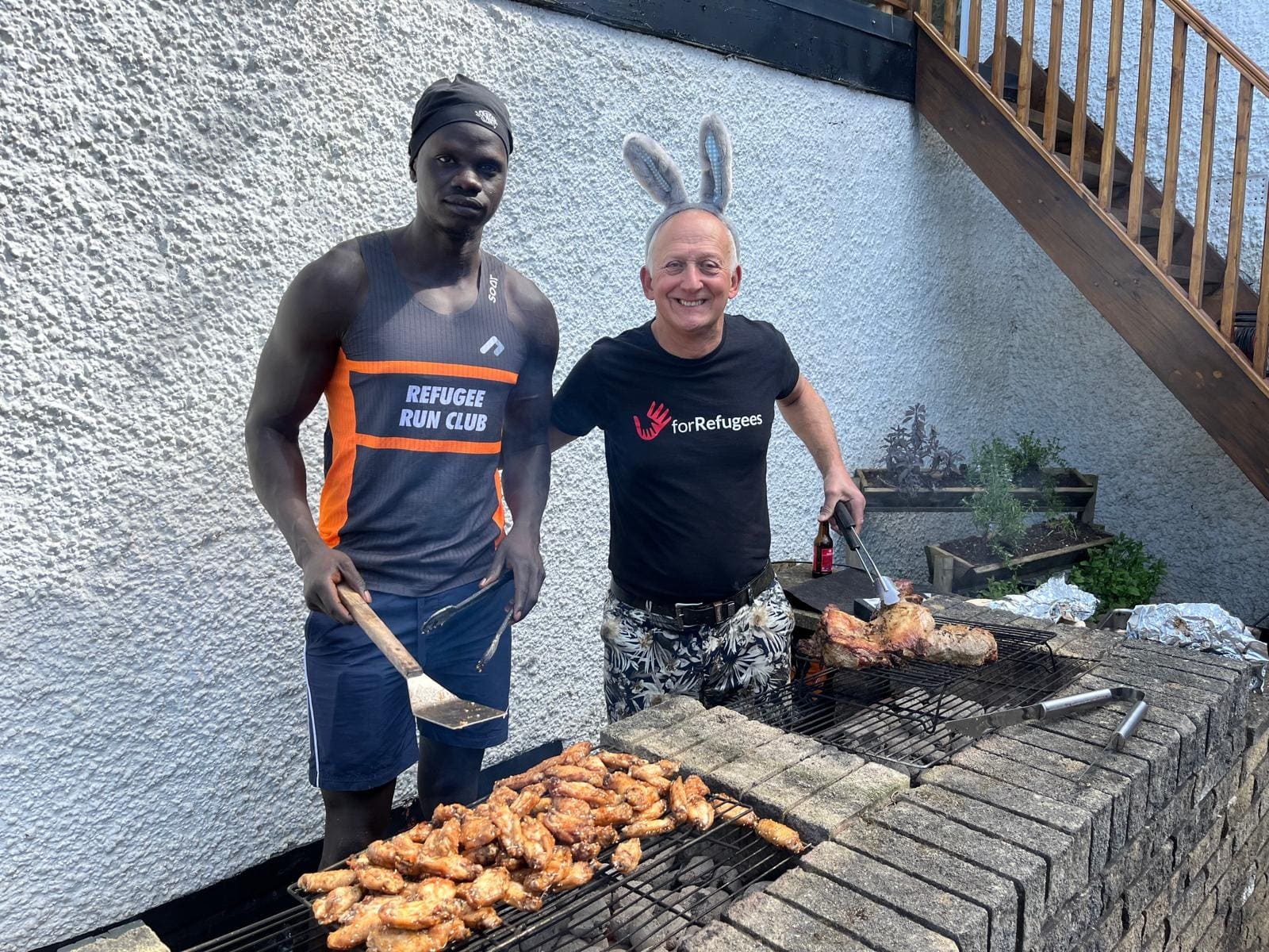 Hähnchen auf dem Grill, an dem ein Mitglied des Refugee Run Club steht
